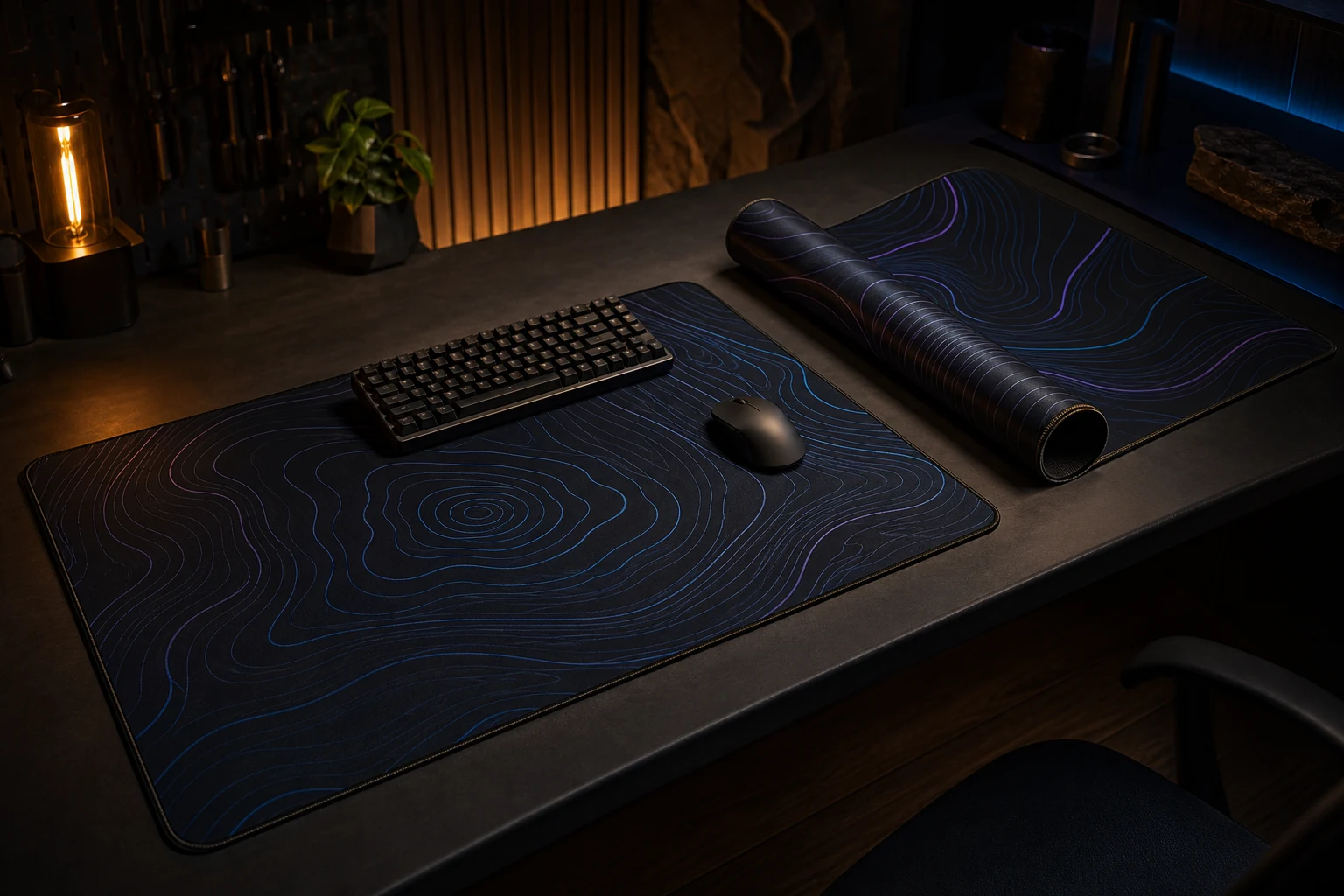 Two dark stitched desk mats with subtle cyan and violet contour patterns in a night workshop.